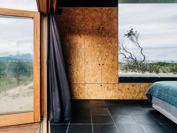Деревянный домик в стиле &laquo;Tiny-house&raquo; среди песчаных дюн